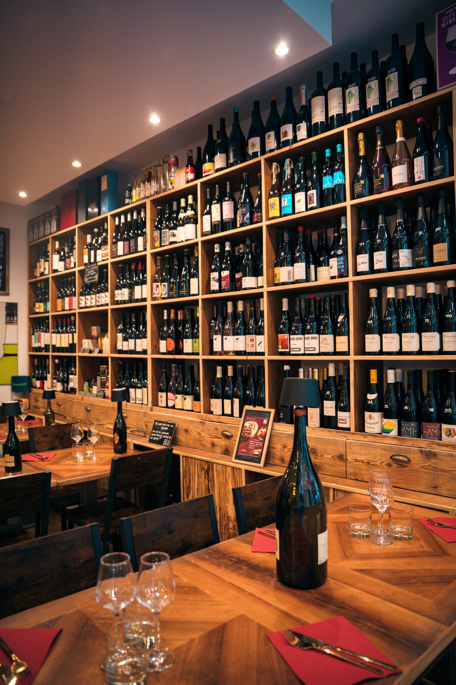 Mur de bouteilles de la cave de vins naturels du Bistrot du Fromager, tables dressées